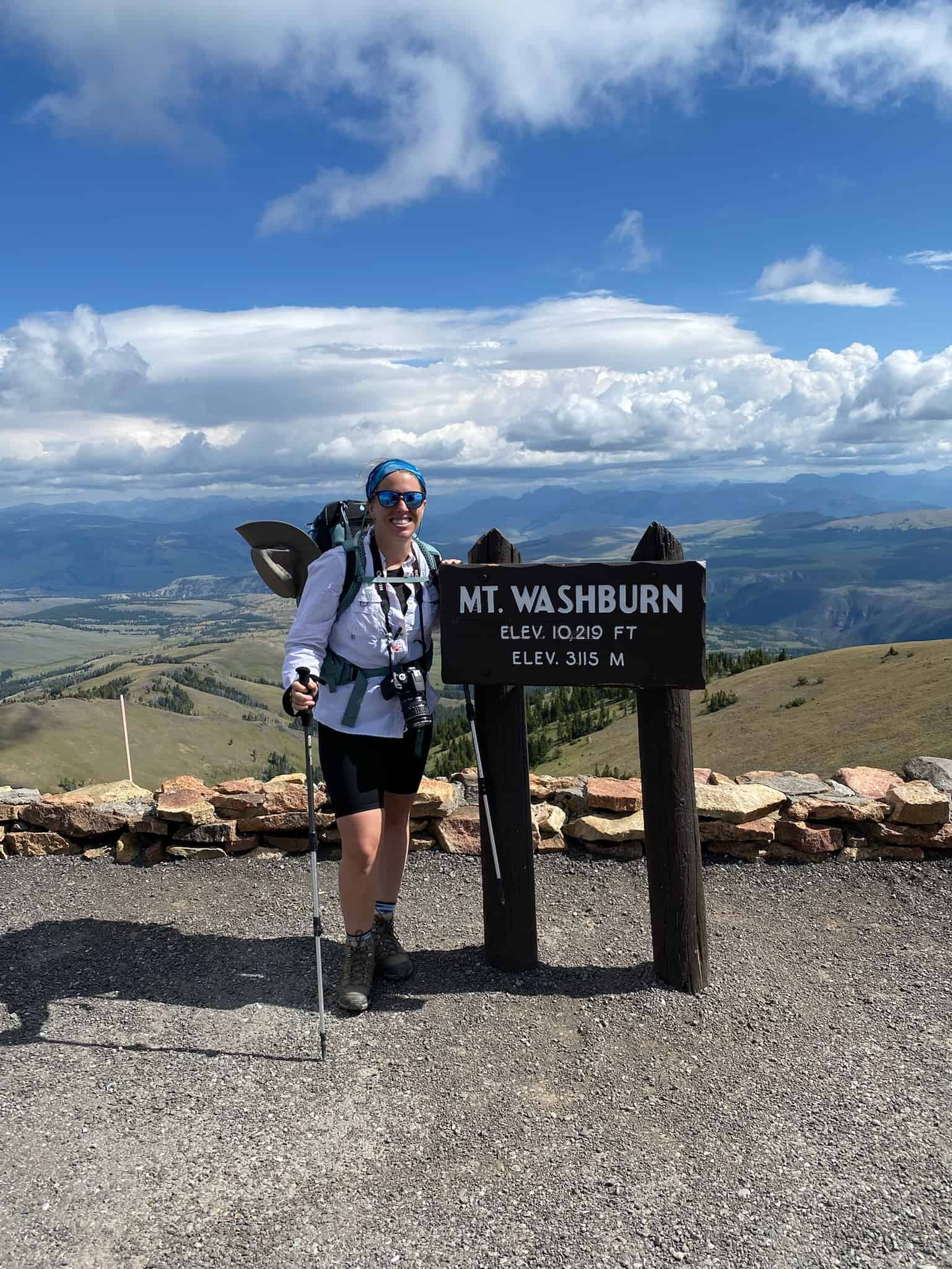 Woman at the top of a peak with Mt.Washburn sign 