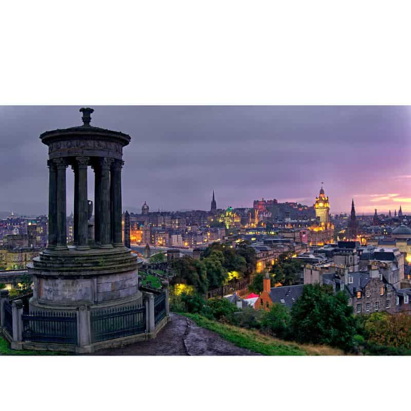 Calton Hill with Edinburgh city in the background with pink and purple skies 