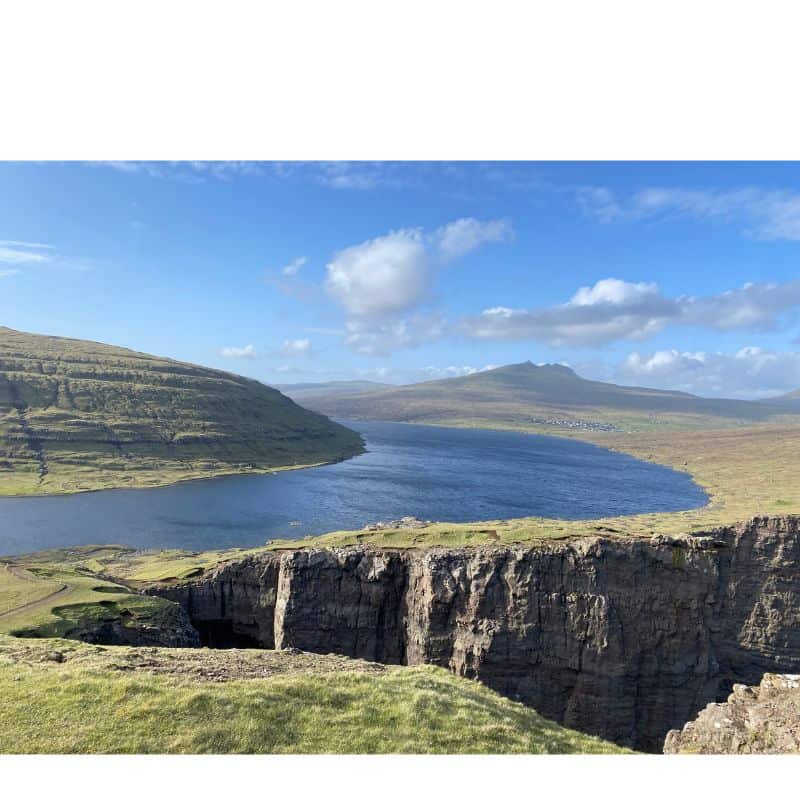 Vagar Island with lake at the edge of a cliff with green mountains 