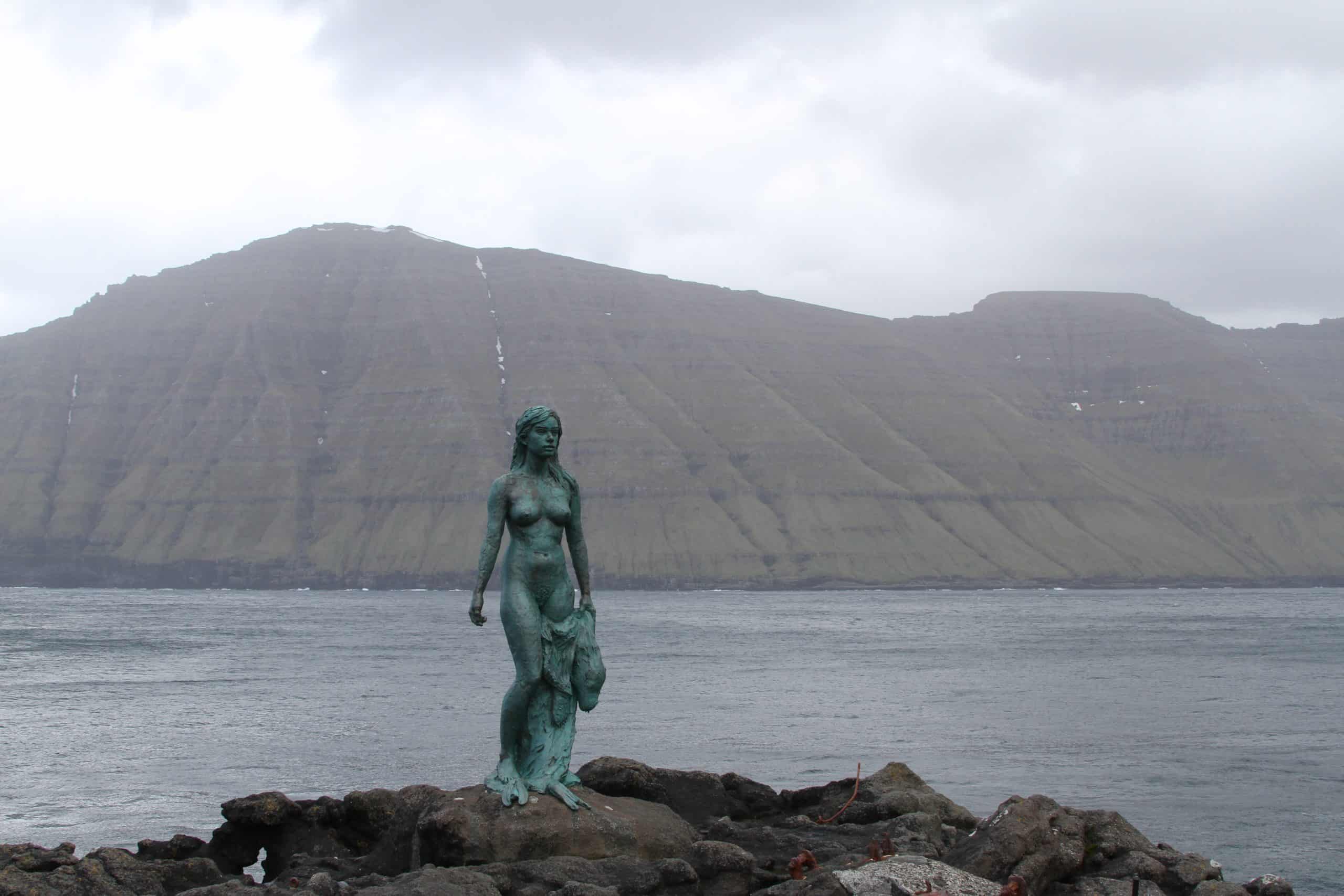 mermaid statue with mountains and ocean behind