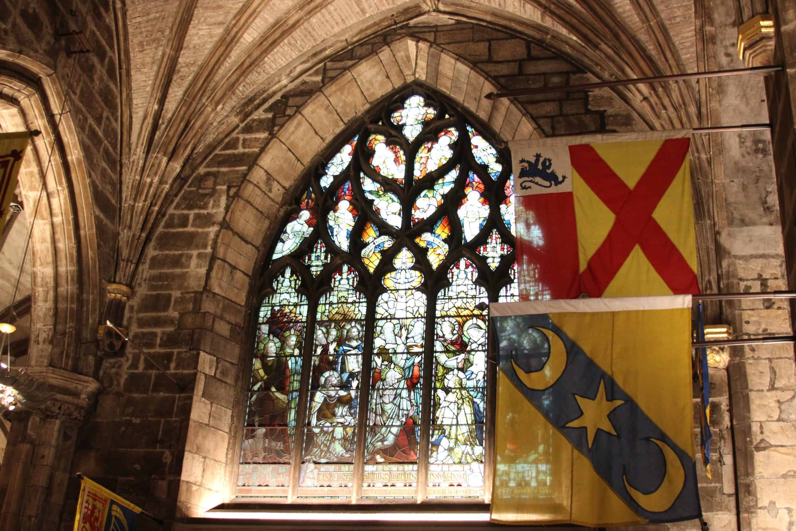 Visit St. Gile's Cathedral, stained glass windows with traditional flags hanging 