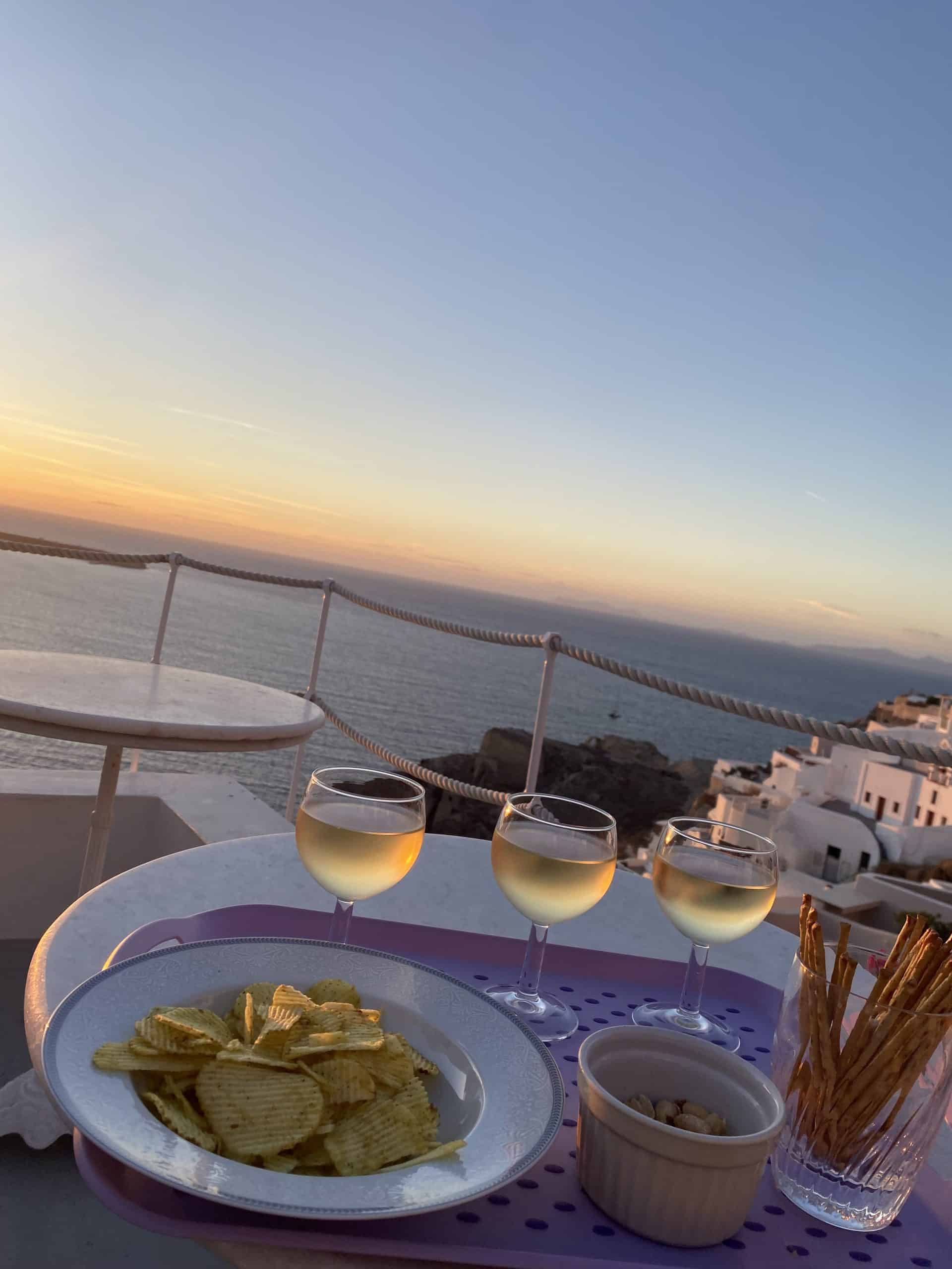 three glasses of wine with Greek buildings and ocean in the background 