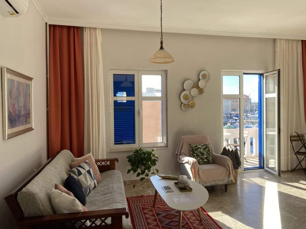 living room with furniture and balcony with boats and harbor in the background 