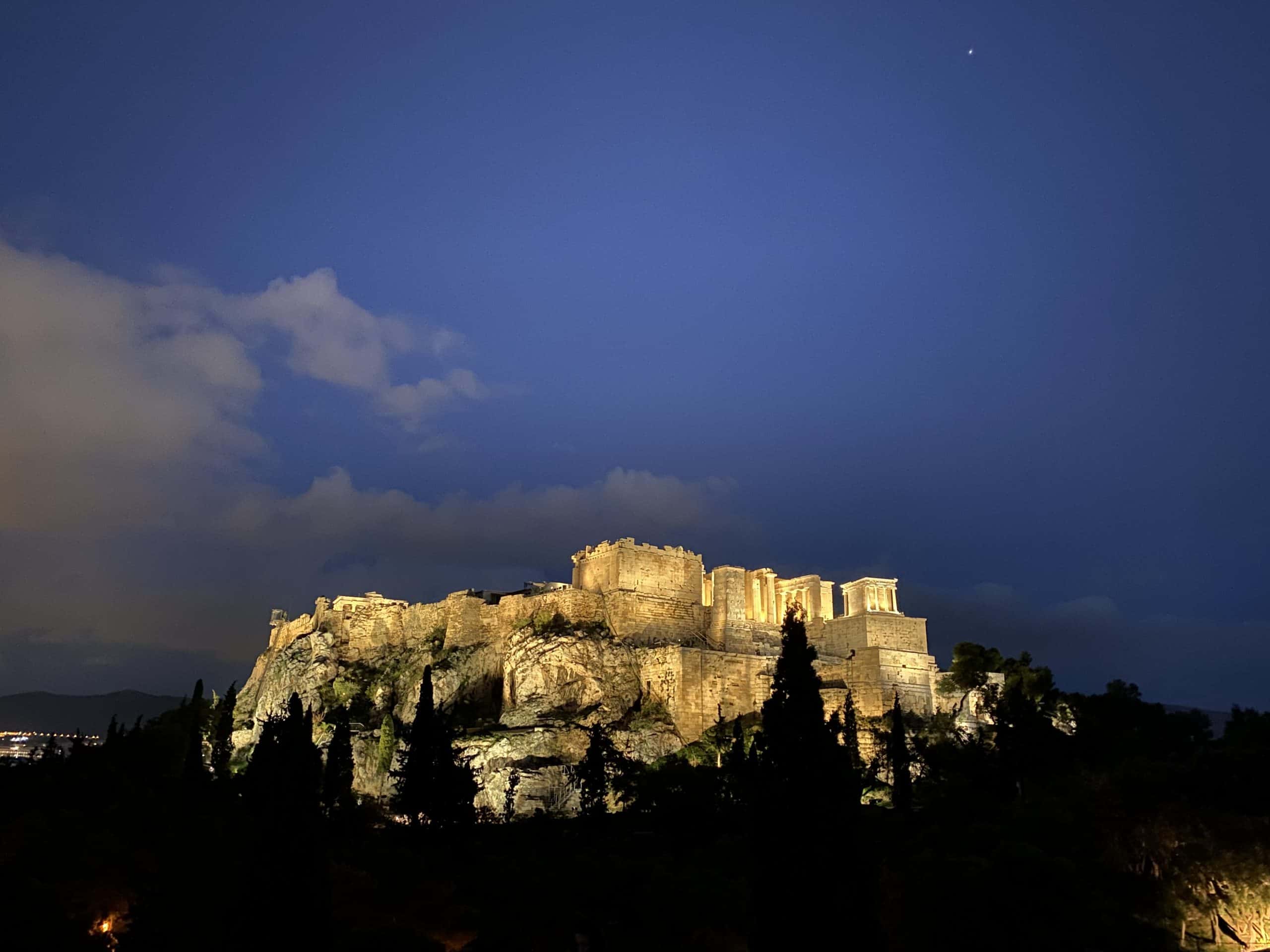 Acropolis lit up at night with clouds