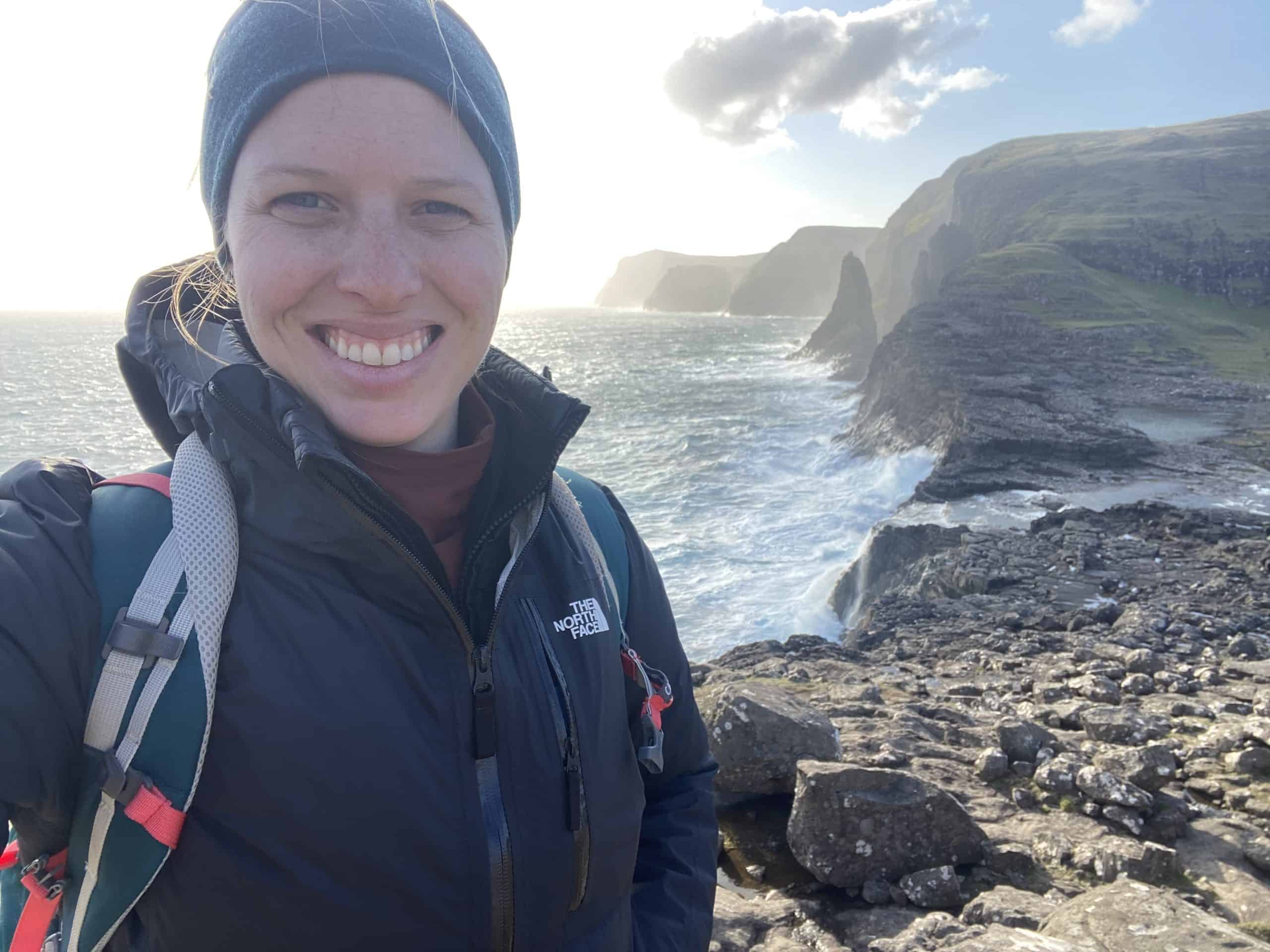 Woman with ocean and cliffs in background of Faroe Islands 
