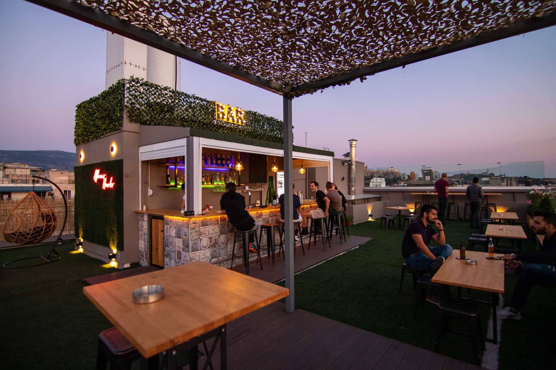 Rooftop bar with people drinking and eating at picnic tables 