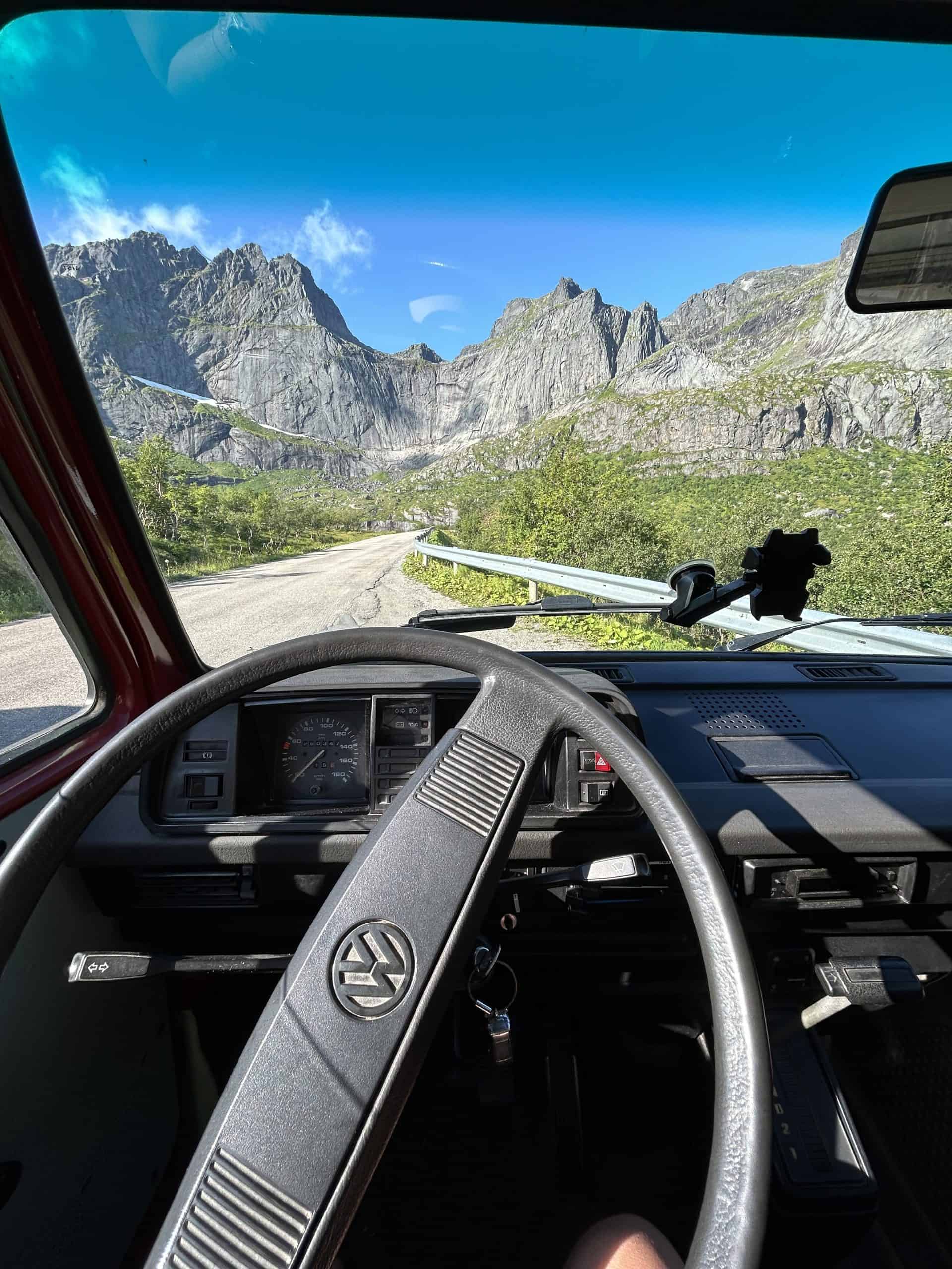 Inside dashboard of Volkswagen van with panoramic mountains in the window. 