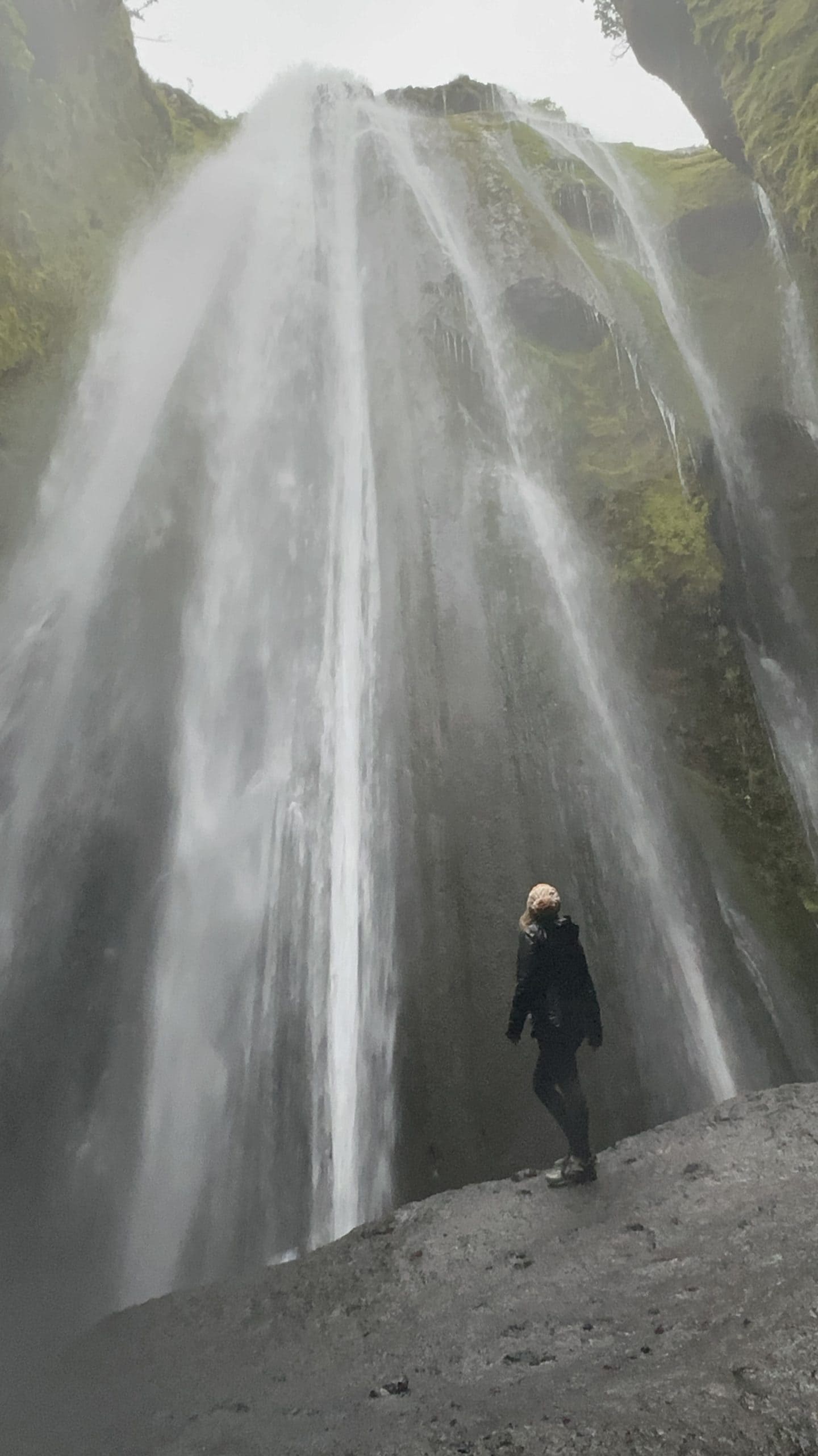 Hidden waterfall in Iceland with woman looking at waterfall. 