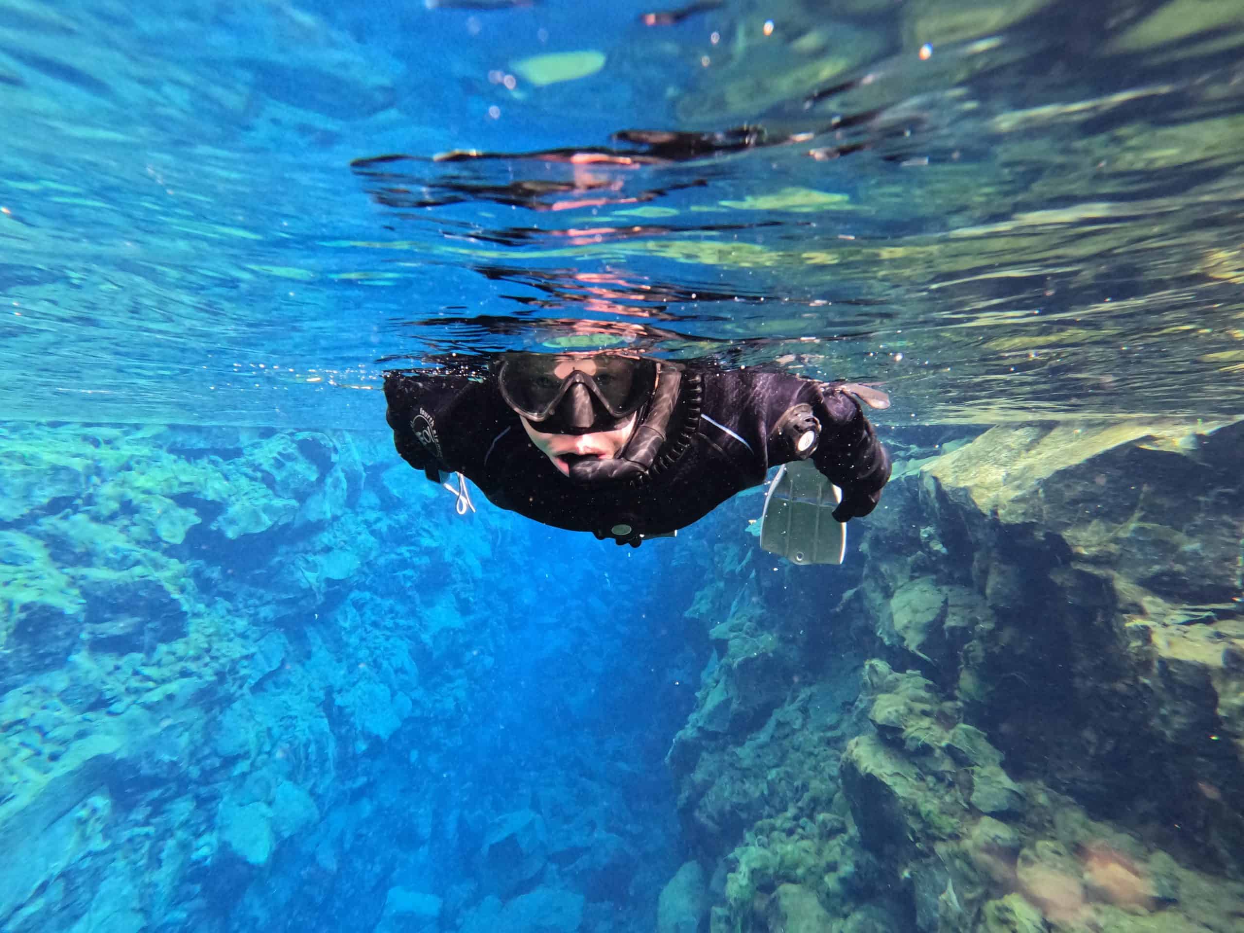 Woman snorkeling in Silfra Fissure, clear blue water. 